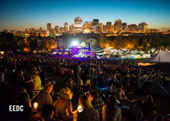 Foule appréciant le festival folklorique d'Edmonton en plein air la nuit.
